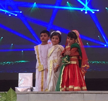 Children in traditional dress on stage at a school